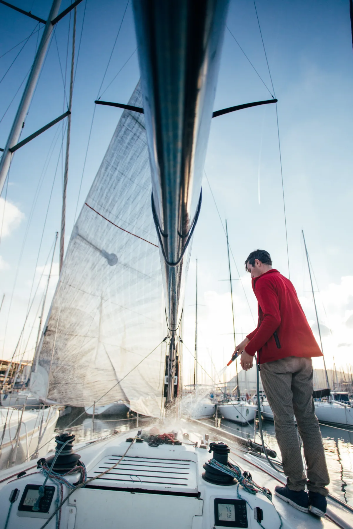 Propietario lavando la cubierta de un velero atracado antes de ponerlo a la venta